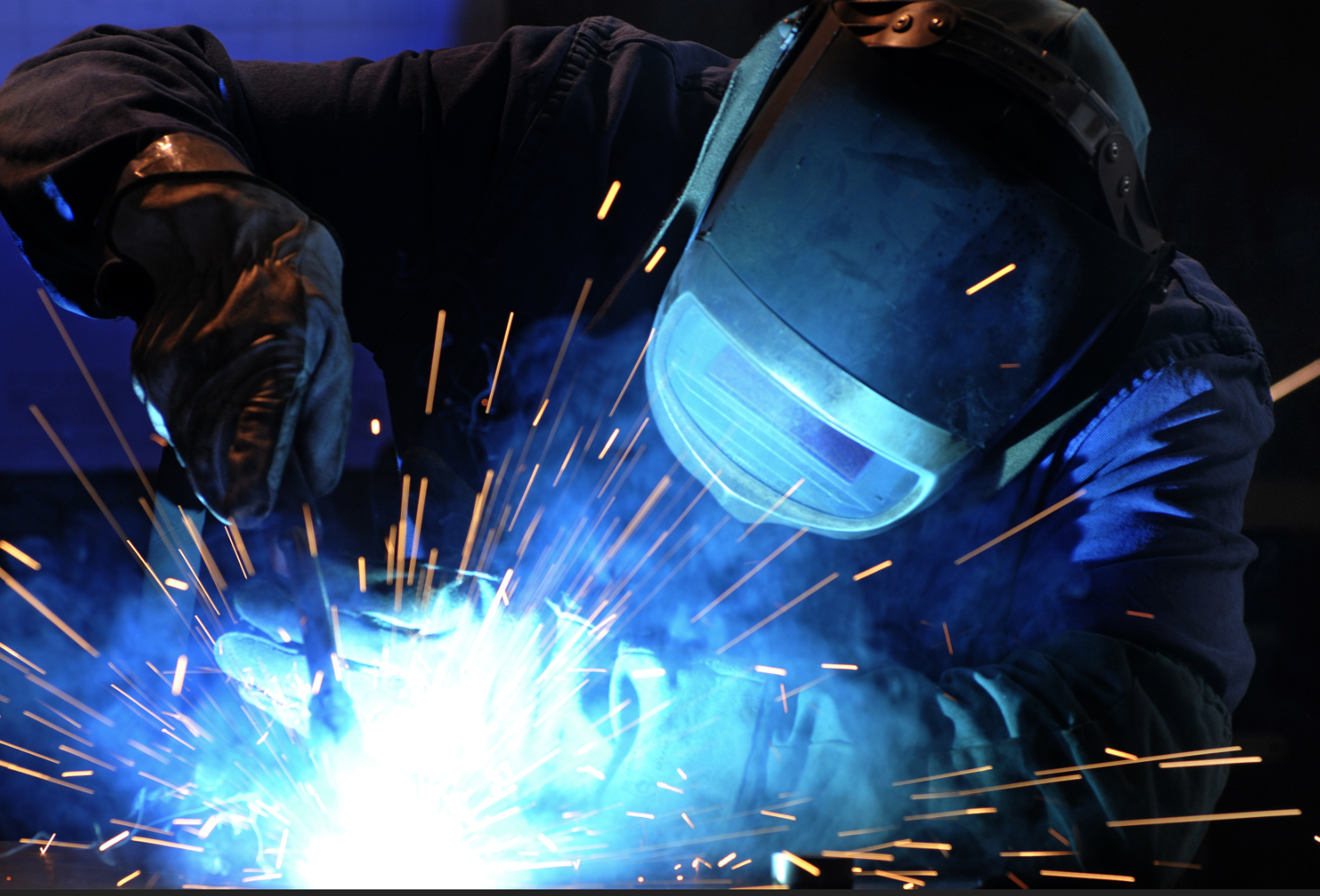 Professional welder with sparks flying during fabrication work showing quality welding services
